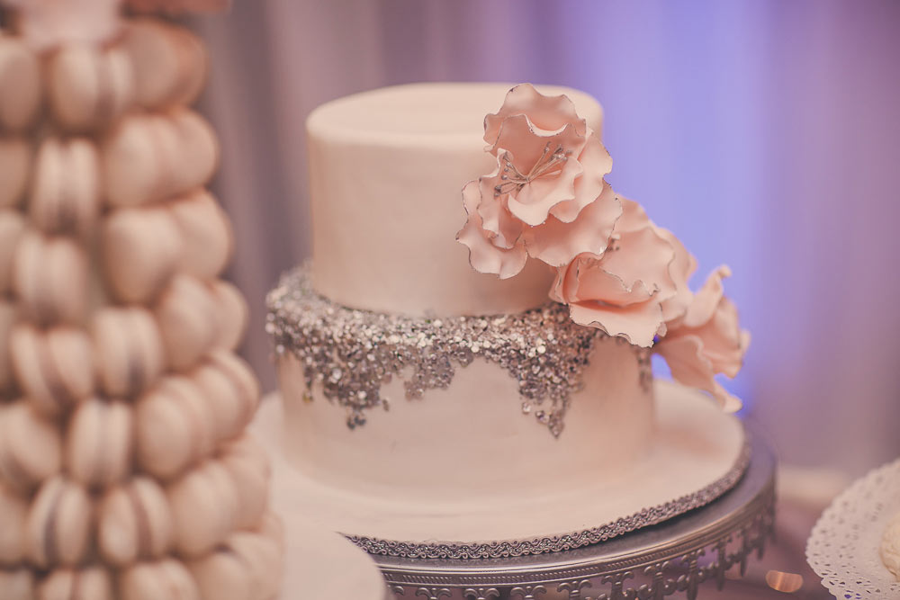 close up of wedding cake with silver glitter and pink flowers