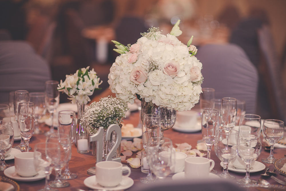 close up of wedding decor showing mercury glass vase with hydrangeas and roses