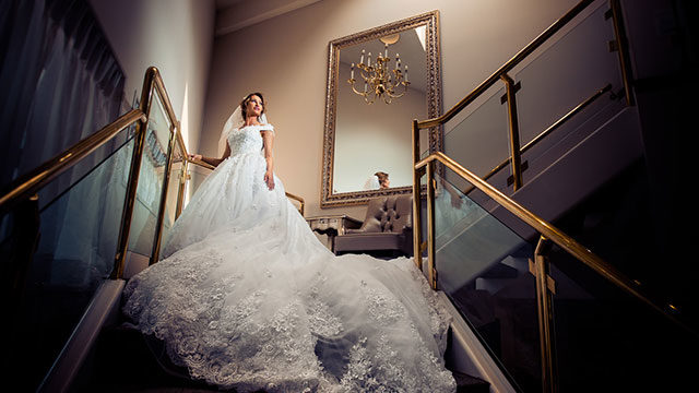 dramatic portrait of bride with wedding gown on gold staircase