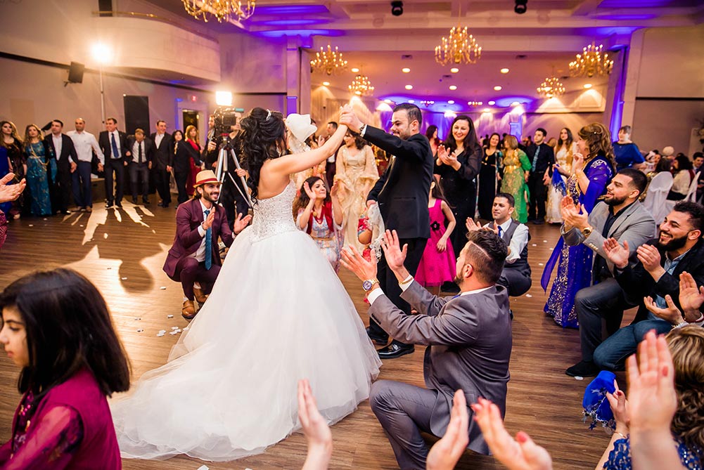 bride and groom have first dance as wedding guests clap