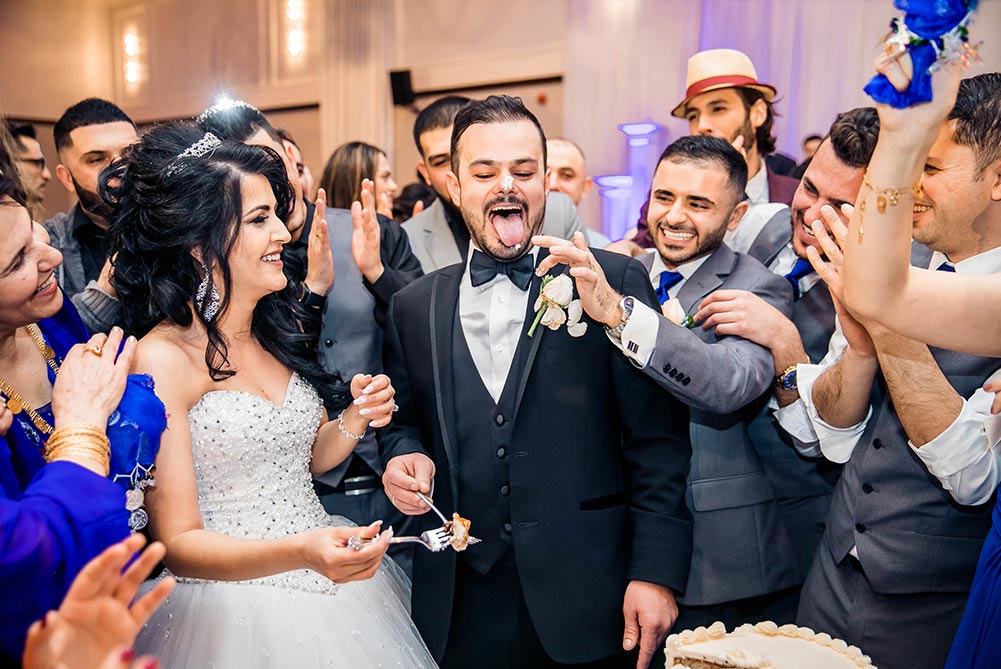 Bride and groom celebrate first bite of wedding cake with bridal party