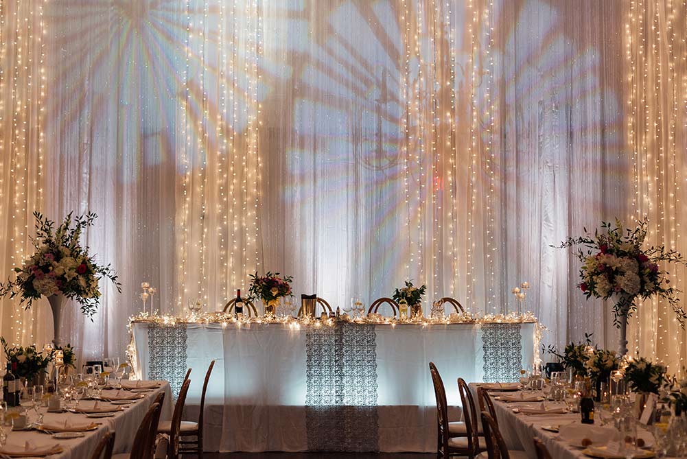 head table wedding decor with hanging fairy lights and floral centerpieces