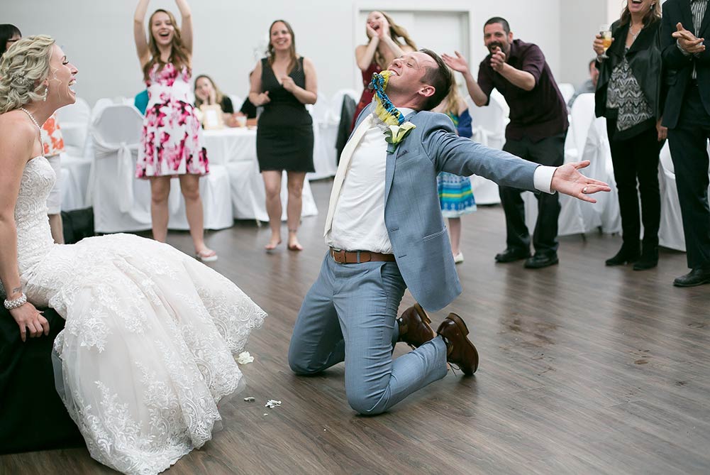 groom holding bride's garter in mouth during game at wedding reception