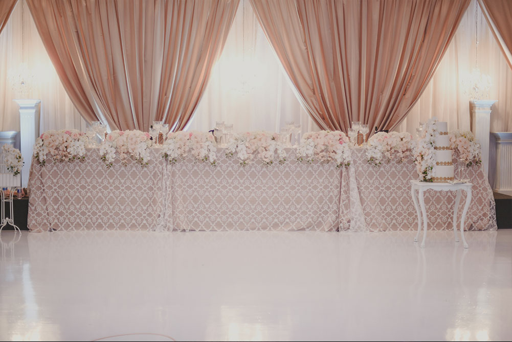 view of head table at wedding with taupe drapes and handing flowers