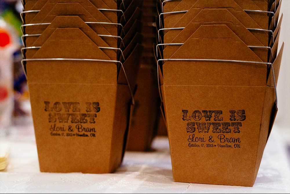 close up of takeout boxes printed with "love is sweet" for candy bar at wedding reception