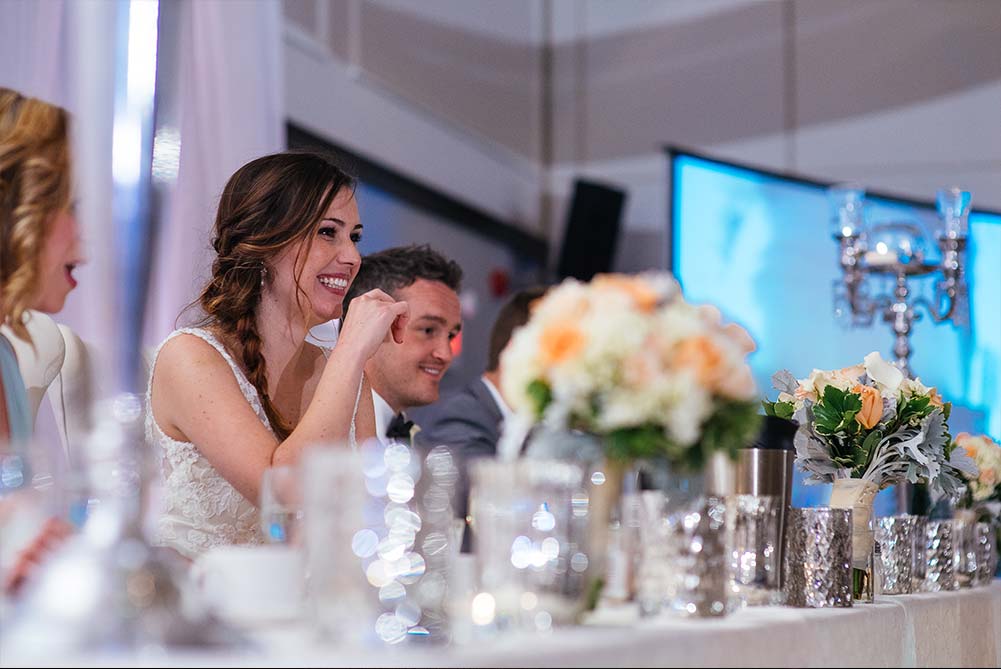 candid shot of bride and groom laughing during wedding speeches
