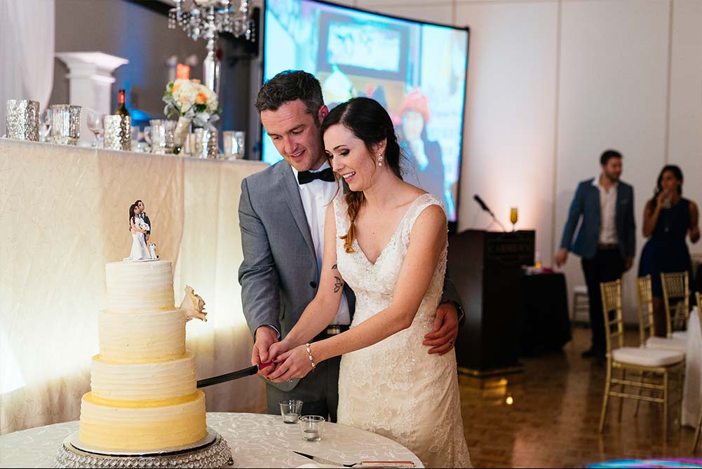 bride and groom holding hands as they cut wedding cake