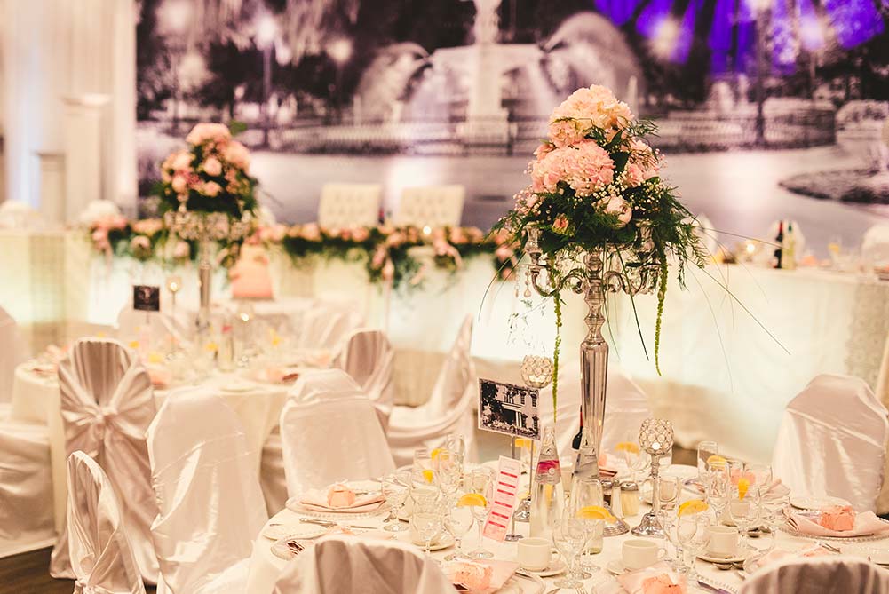 close up of wedding table decor with white satin chair covers and silver candelabras