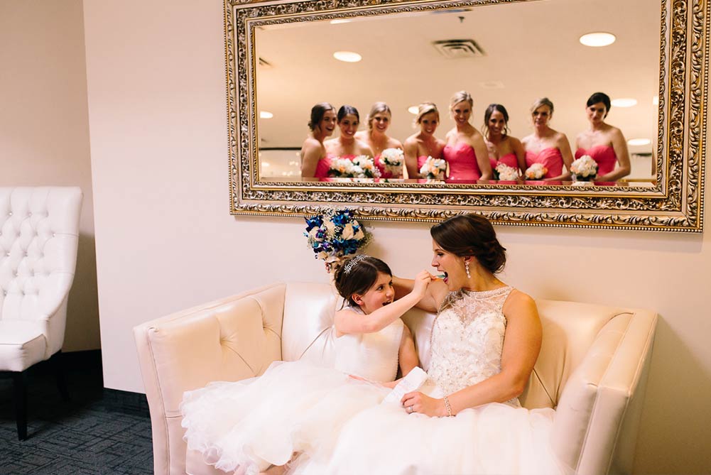 bride and flower girl sharing food on white sofa