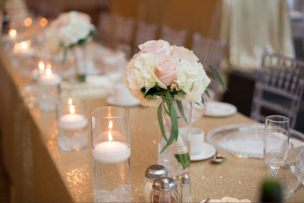close up of wedding decor showing floating candles and vases with floral bouquets