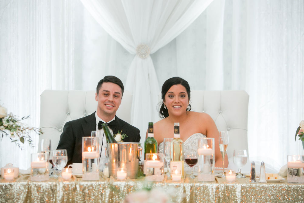 shot of bride and groom sitting at head table during their wedding reception