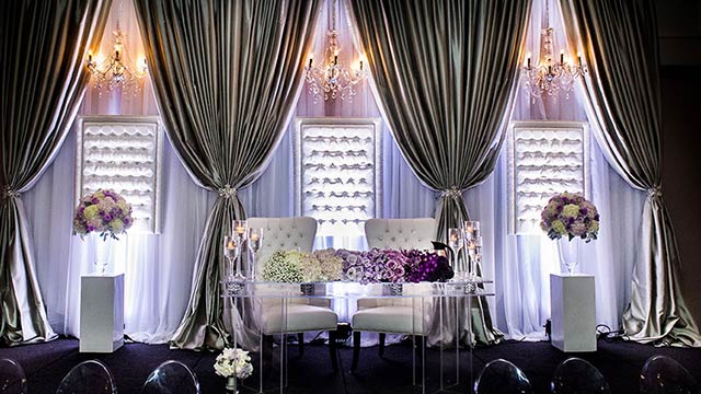 acrylic sweetheart head table with chandeliers and drapes