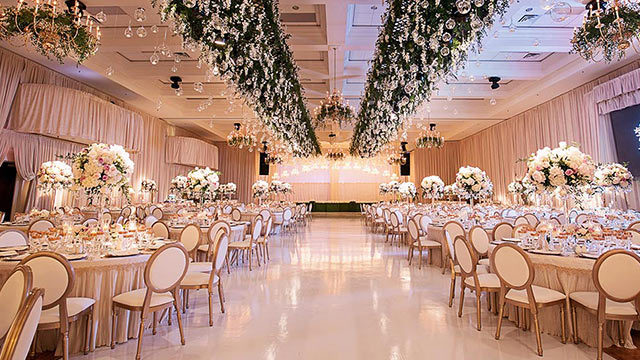 ivory wedding decor in ballroom at Carmen's with hanging florals and gold King Louie chairs